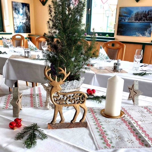 Festlich gedeckter Tisch für ein Weihnachtsbuffet mit einer Auswahl an festlichen Gerichten, darunter gebratenes Fleisch, herzhafte Beilagen und bunte Salate. Der Tisch ist weihnachtlich dekoriert mit Kerzen, Ornamenten und roten und grünen Servietten. Da